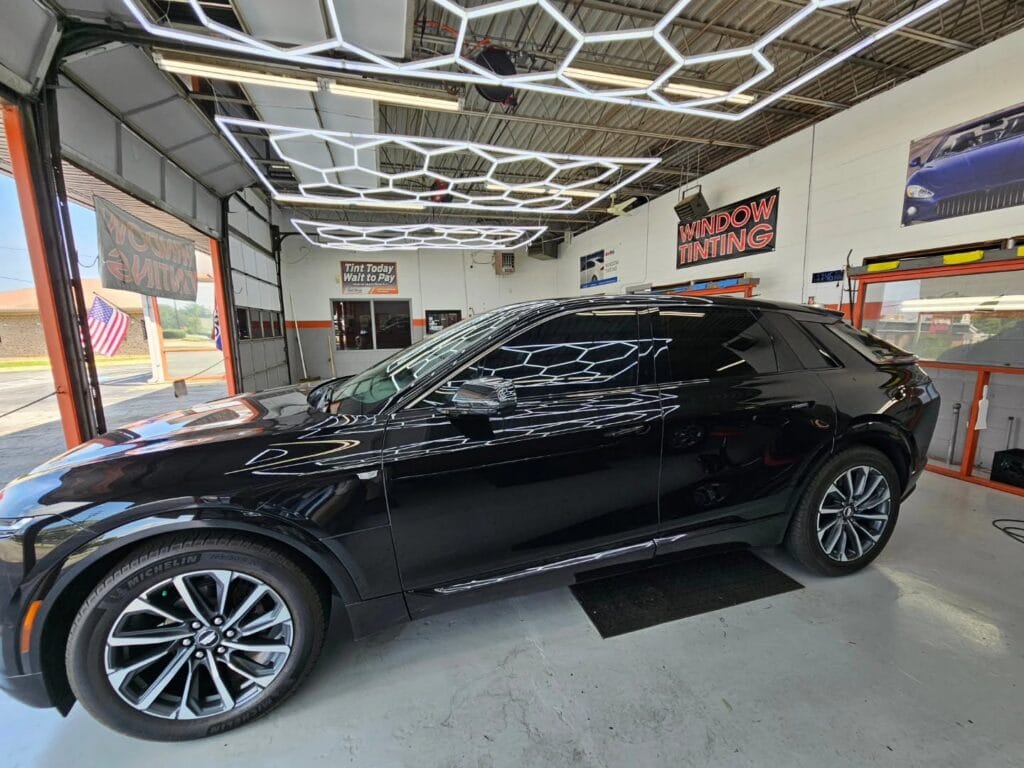 Black vehicle with tinted windows inside the lab of The Tint Shop