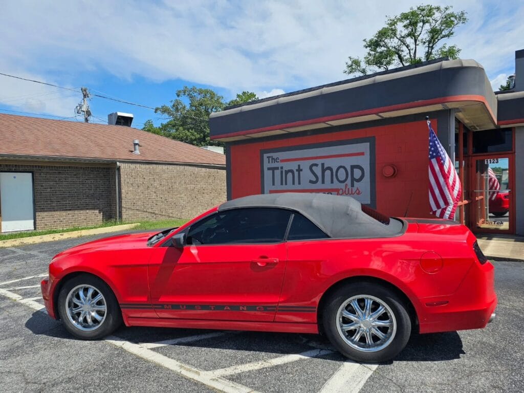 Red vehicle with tinted windows parked outside of The Tint Shop