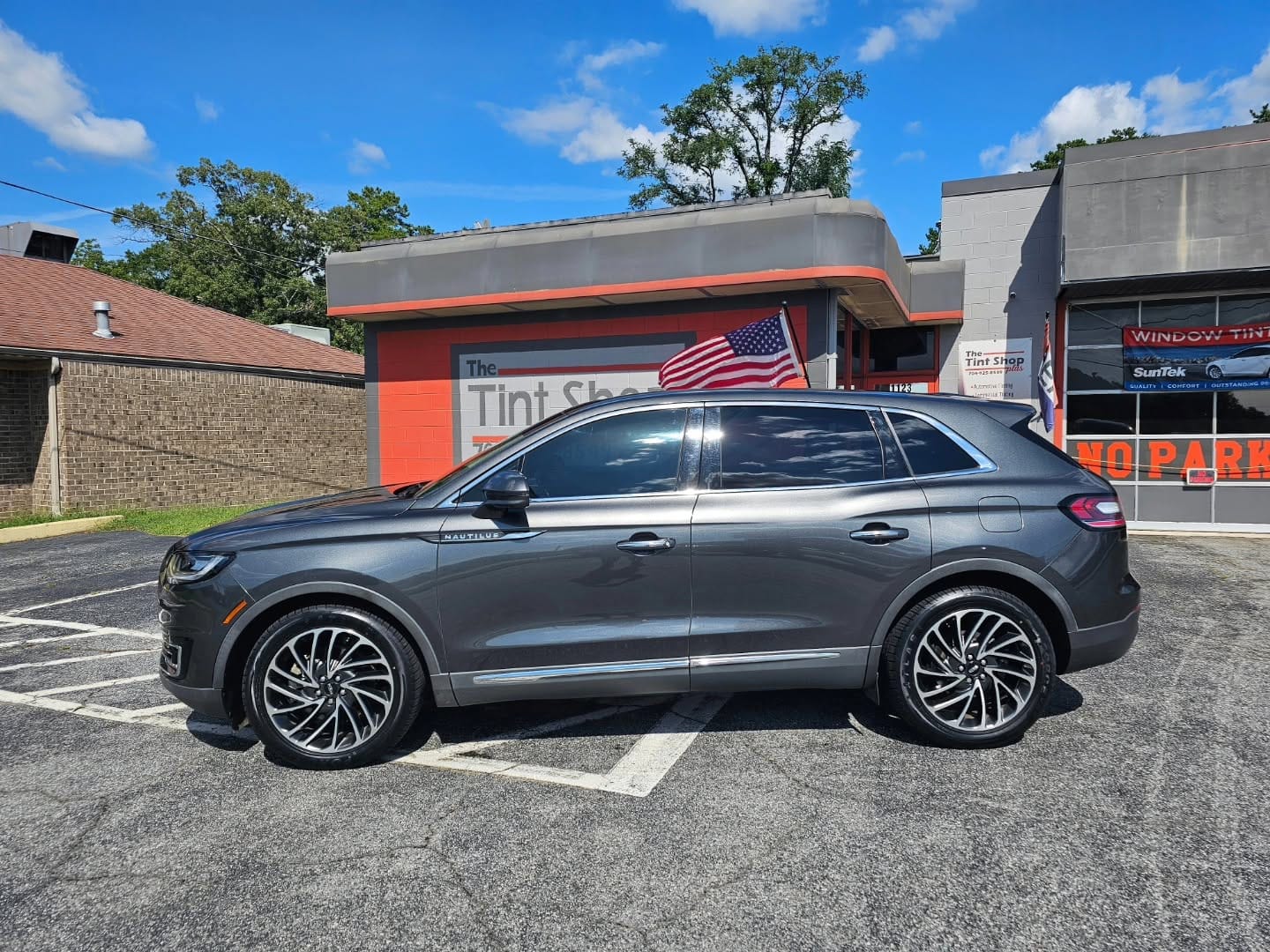 Side view of a parked vehicle with tinted windows outside of The Tint Shop Plus